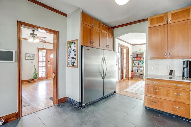 kitchen featuring arched walkways, dark wood finished floors, stainless steel refrigerator, crown molding, and backsplash