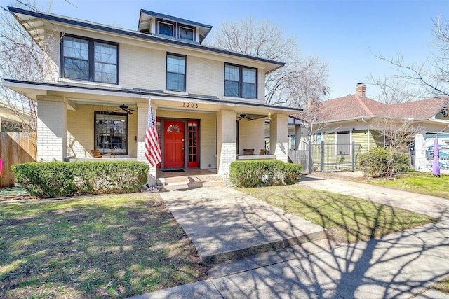 traditional style home featuring a porch, brick siding, fence, and a ceiling fan