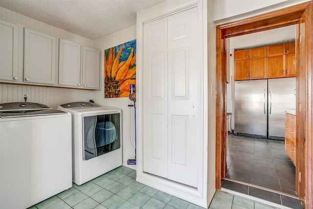 laundry room with light tile patterned flooring, cabinet space, a textured ceiling, and separate washer and dryer