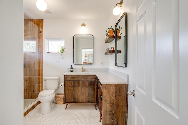 bathroom featuring visible vents, tiled shower, toilet, tile patterned flooring, and vanity