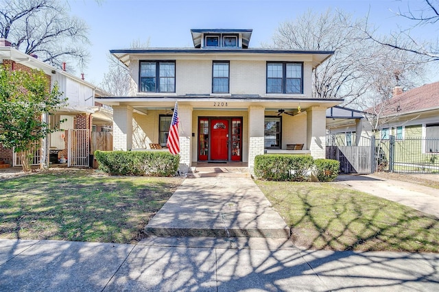 american foursquare style home featuring covered porch, a gate, fence, a front lawn, and brick siding