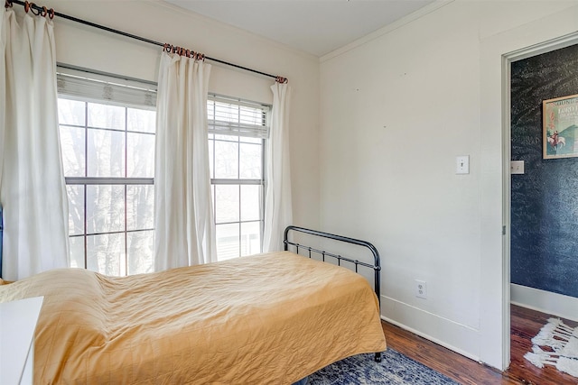 bedroom featuring baseboards, wood finished floors, and crown molding