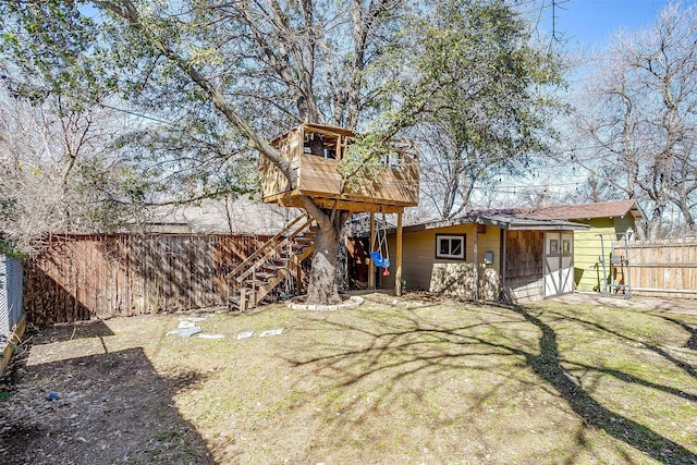 view of yard with a deck, stairway, an outbuilding, and fence