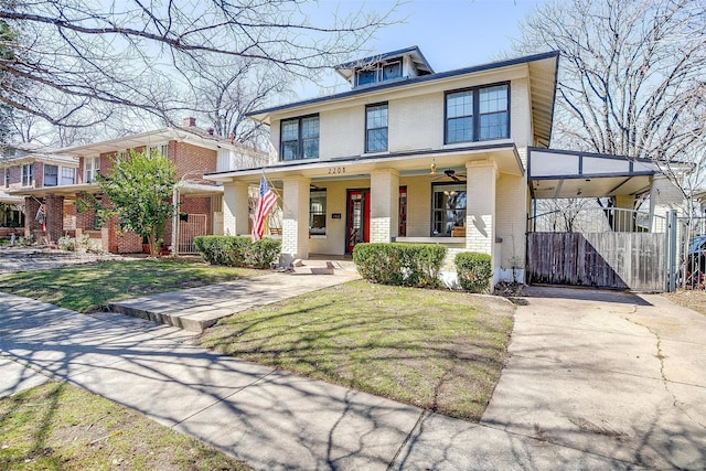 american foursquare style home with brick siding, covered porch, a front yard, a gate, and an attached carport