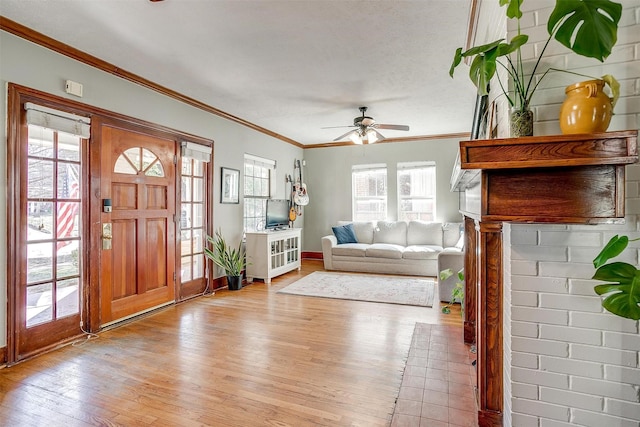 entryway featuring ornamental molding, ceiling fan, light wood finished floors, and baseboards