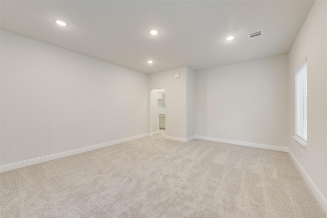 spare room with baseboards, recessed lighting, visible vents, and light colored carpet