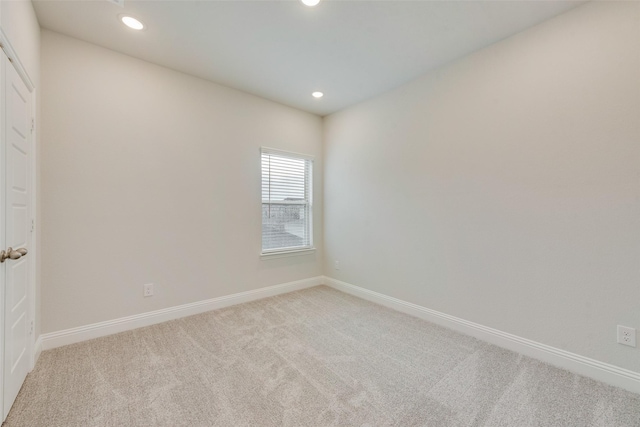 empty room featuring recessed lighting, baseboards, and light colored carpet