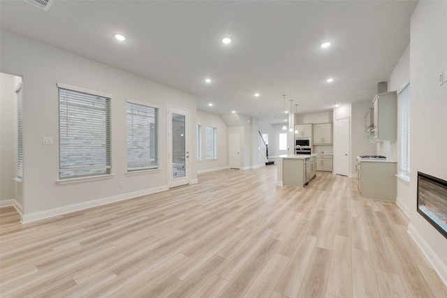 unfurnished living room with light wood finished floors, baseboards, and recessed lighting