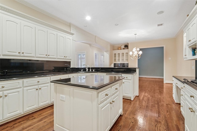 kitchen featuring dark countertops, a notable chandelier, a peninsula, and wood finished floors