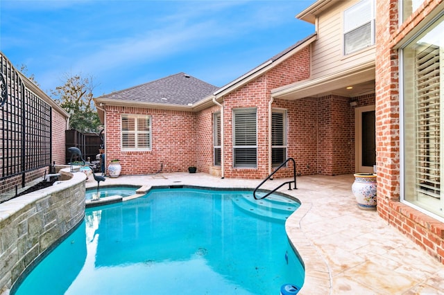 view of swimming pool with a patio area, fence, and a pool with connected hot tub