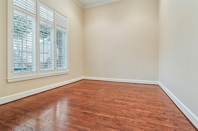 spare room with ornamental molding, baseboards, and wood finished floors