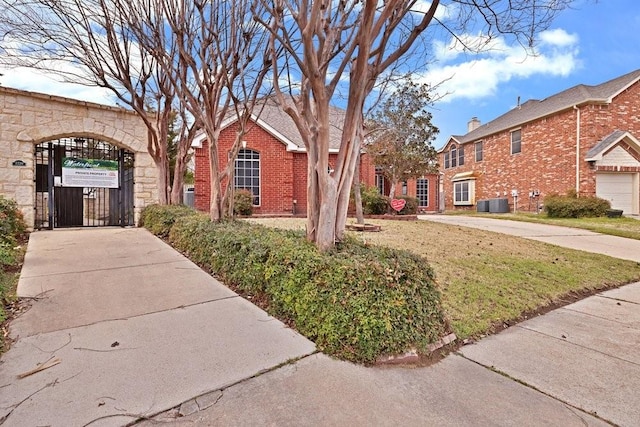 view of front of property featuring a gate, brick siding, and central AC