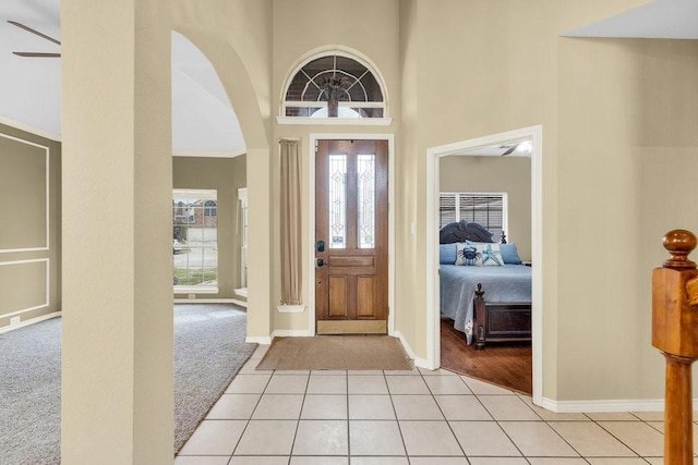 entrance foyer featuring light colored carpet, plenty of natural light, a towering ceiling, and light tile patterned floors