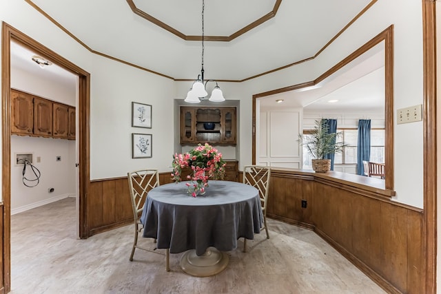 dining room with a tray ceiling, wainscoting, crown molding, and wooden walls