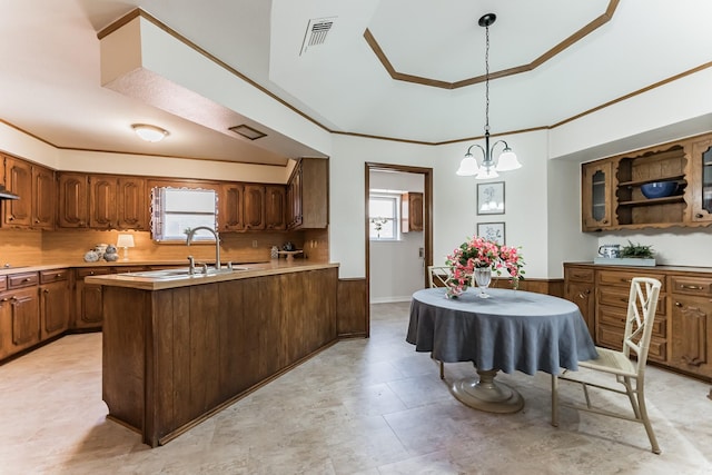 kitchen with crown molding, tasteful backsplash, a raised ceiling, light countertops, and a sink