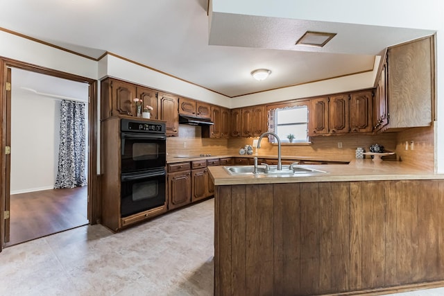 kitchen with decorative backsplash, a peninsula, under cabinet range hood, black appliances, and a sink