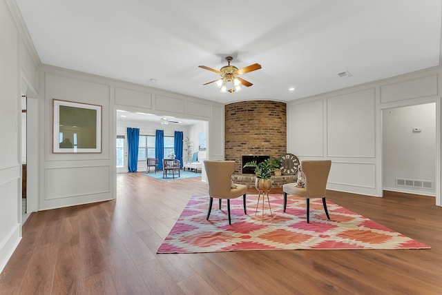 living area with visible vents, a decorative wall, and wood finished floors