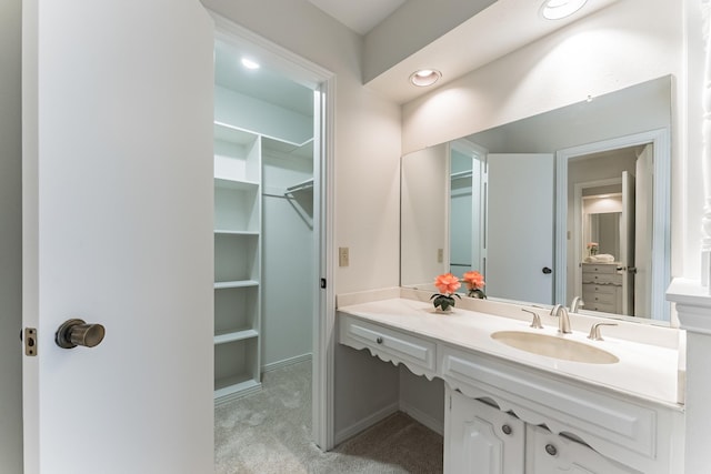 bathroom featuring a spacious closet, vanity, and recessed lighting