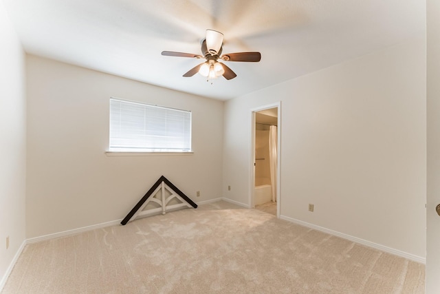 carpeted spare room featuring a ceiling fan and baseboards