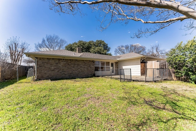 back of house featuring a sunroom, a fenced backyard, a chimney, a yard, and brick siding