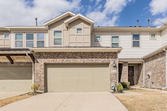 view of property with an attached garage, concrete driveway, and brick siding