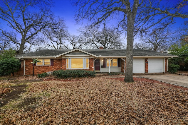 ranch-style home featuring driveway, an attached garage, a chimney, and brick siding