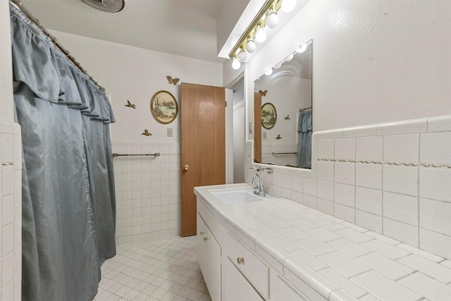 bathroom with wainscoting, a shower with curtain, tile walls, and vanity