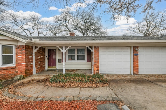 exterior space with driveway, a garage, a chimney, and brick siding