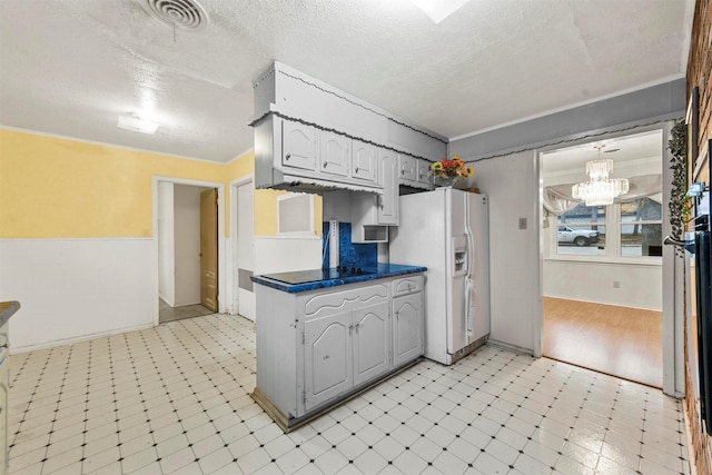 kitchen with visible vents, dark countertops, a textured ceiling, light floors, and white fridge with ice dispenser