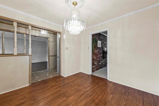 unfurnished dining area with crown molding, a notable chandelier, baseboards, and wood finished floors