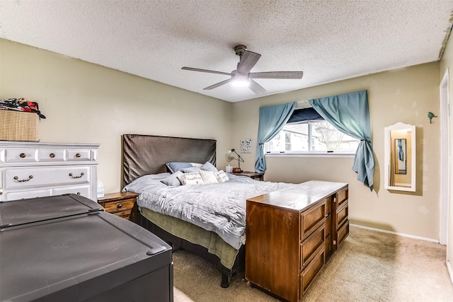 bedroom with a ceiling fan, light colored carpet, a textured ceiling, and baseboards