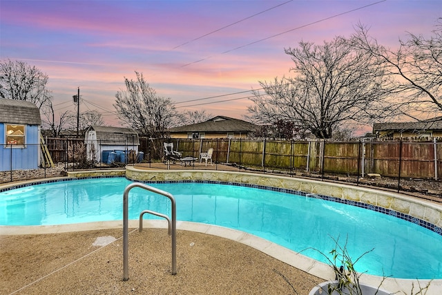 pool at dusk with a fenced in pool, a fenced backyard, a patio, and an outdoor structure