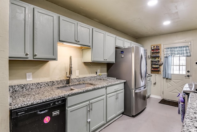 kitchen featuring finished concrete floors, freestanding refrigerator, a sink, light stone countertops, and dishwasher