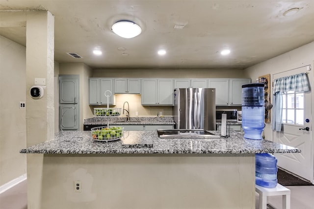 kitchen featuring appliances with stainless steel finishes, a sink, light stone counters, and a kitchen bar