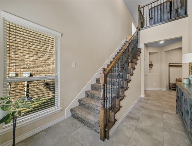 stairway with a towering ceiling and baseboards