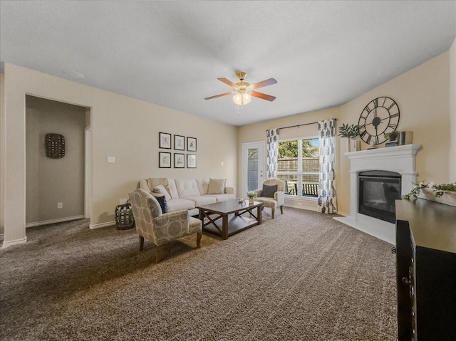 living area with carpet, baseboards, ceiling fan, and a fireplace with flush hearth