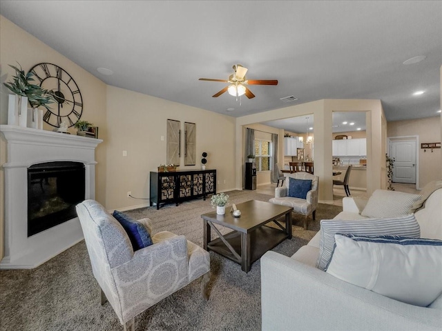 carpeted living area with ceiling fan, visible vents, baseboards, and a glass covered fireplace