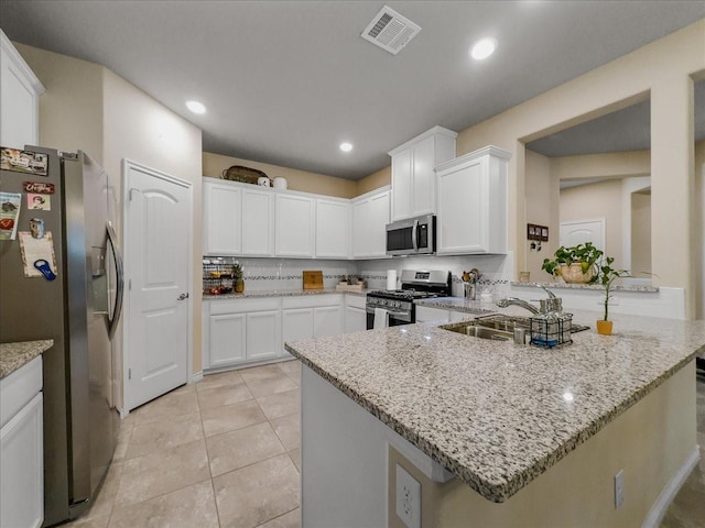 kitchen with stainless steel appliances, visible vents, white cabinetry, a sink, and a peninsula