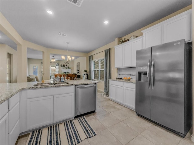 kitchen featuring stainless steel appliances, a sink, light stone countertops, and white cabinets