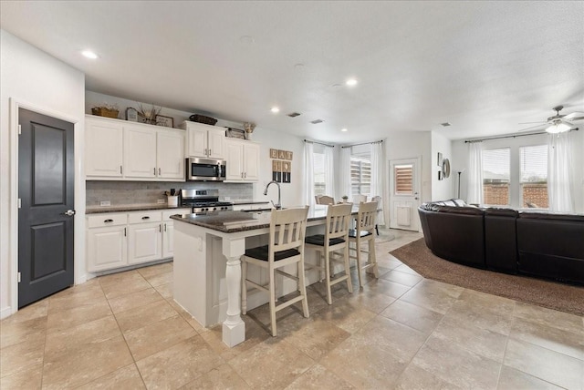 kitchen with appliances with stainless steel finishes, open floor plan, a kitchen island with sink, a kitchen bar, and a sink