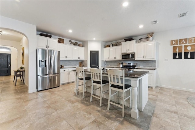 kitchen with visible vents, appliances with stainless steel finishes, arched walkways, and backsplash