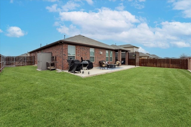 back of house with a yard, a patio, brick siding, and a fenced backyard