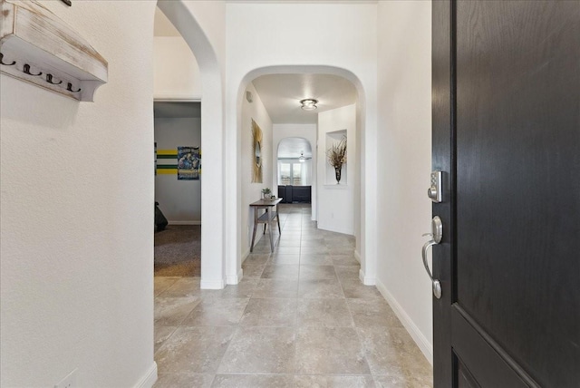 foyer entrance with arched walkways and baseboards