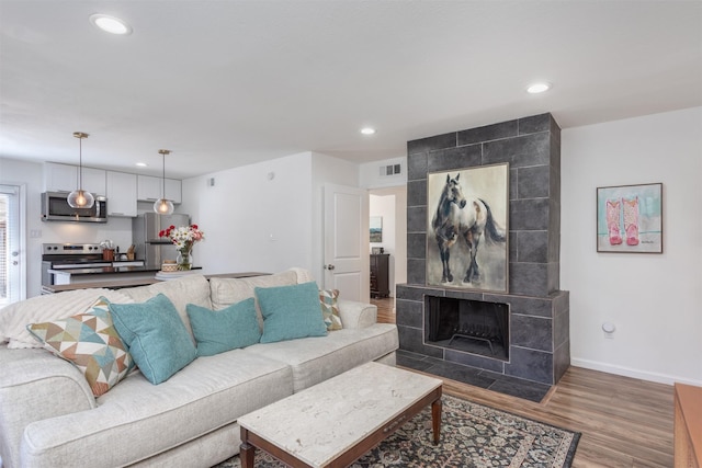 living area featuring visible vents, baseboards, wood finished floors, and recessed lighting