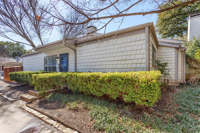 view of side of home featuring a chimney and fence