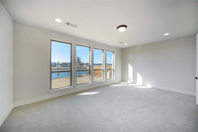 spare room with visible vents, baseboards, a water view, carpet, and recessed lighting