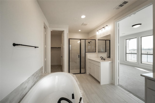 bathroom with a shower stall, a spacious closet, visible vents, and vanity