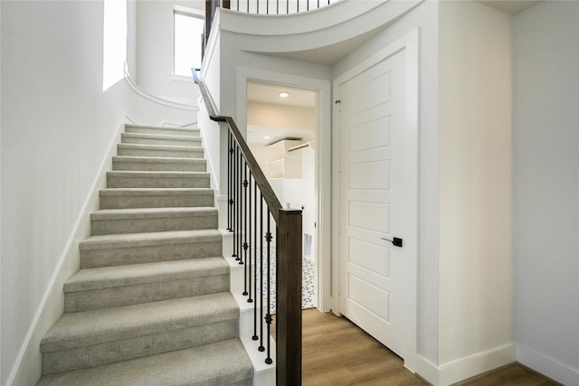 staircase with baseboards and wood finished floors