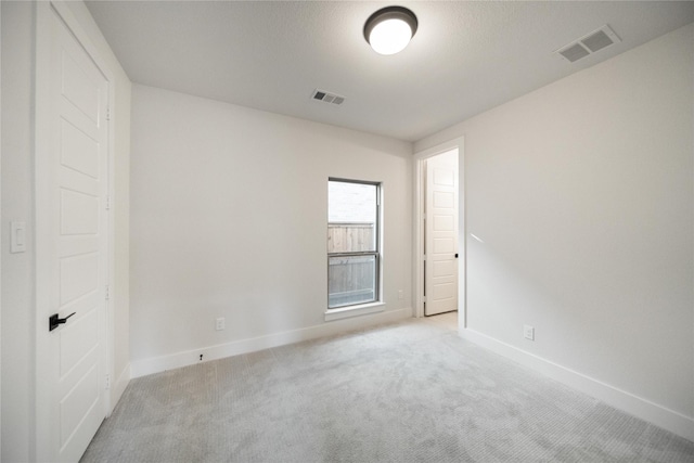 spare room with baseboards, visible vents, and light colored carpet