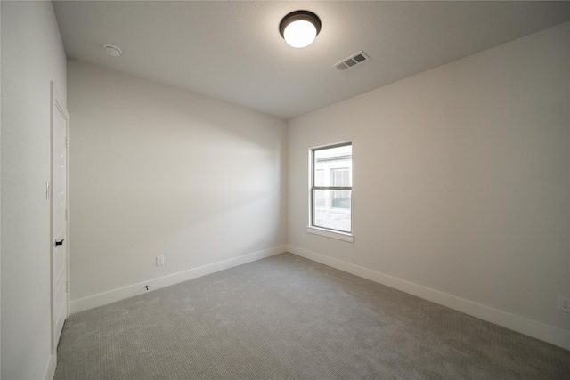 carpeted spare room with visible vents and baseboards